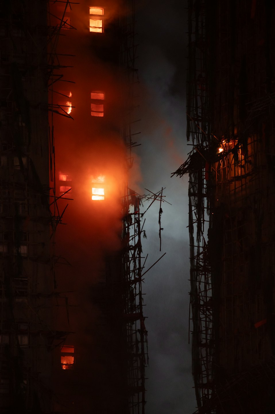 Flames engulf a multi-story building under construction at night.